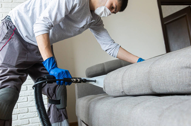 Man cleaning sofa chemical cleaning with professionally extraction method. Upholstered furniture. Early spring cleaning or regular clean up. - Φωτογραφία, εικόνα