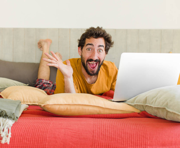 young bearded man on a bed with a laptop - Foto, afbeelding