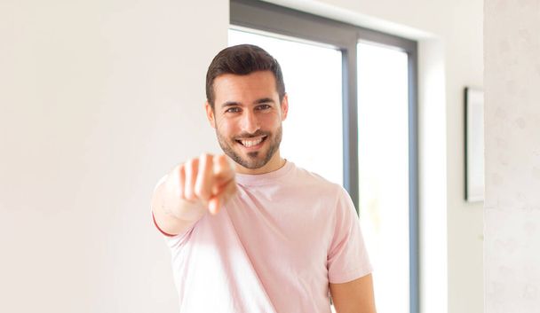 handsome man pointing at camera with a satisfied, confident, friendly smile, choosing you - Foto, Bild