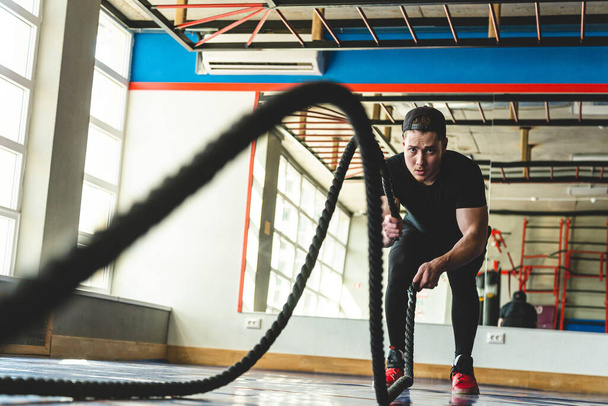 Crossfit with ropes. The athlete is training in the gym opposite large panoramic windows. - Fotografie, Obrázek