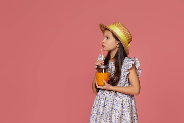 cute little girl in hat with orange juice - Фото, изображение