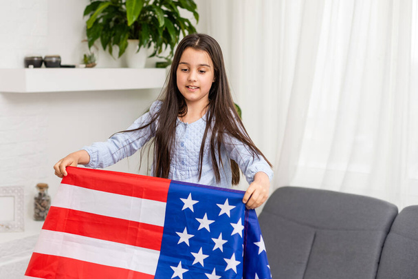 Χαριτωμένο κοριτσάκι και σημαία των ΗΠΑ στο παρασκήνιο - Φωτογραφία, εικόνα