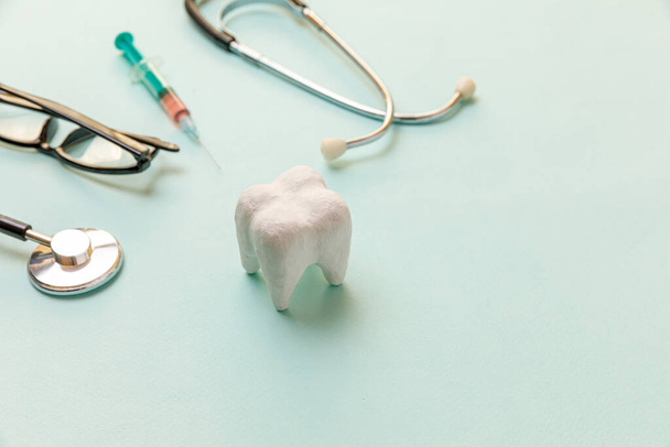 Ιατροδικαστική περίθαλψη. Ιατρικός εξοπλισμός στηθοσκόπιο λευκό υγιή δόντια γυάλινα σύριγγα απομονώνονται σε παστέλ μπλε φόντο. Συσκευή οργάνων για οδοντίατρο. Ημέρα οδοντιατρικής στοματικής υγιεινής - Φωτογραφία, εικόνα