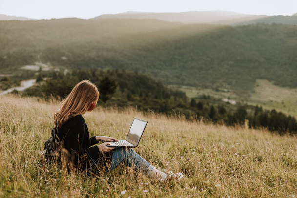 Vrouw met masker werkt op laptop, afgelegen locatie in de natuur - Foto, afbeelding