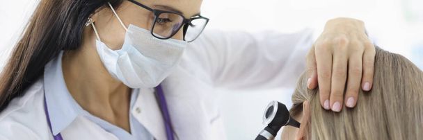 Ωτορινολαρυγγολόγος που εξετάζει γυναίκες ασθενείς αυτί με ωτοσκόπιο στην κλινική - Φωτογραφία, εικόνα