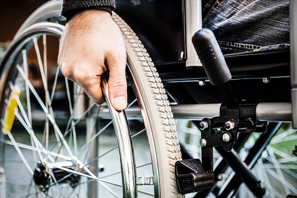 Mies käyttää pyörätuoliaan
 - Valokuva, kuva