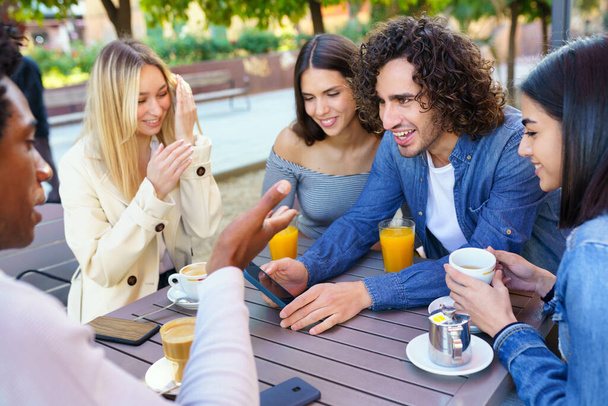Multi-ethnic group of friends having a drink together in an outdoor bar. - Photo, Image