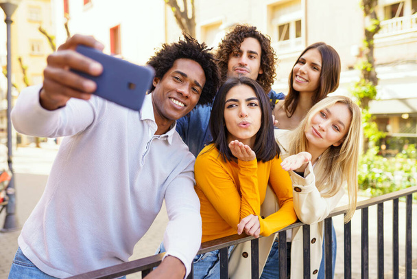 Monietninen ryhmä ystäviä ottaa selfie ulkona älypuhelimella. - Valokuva, kuva