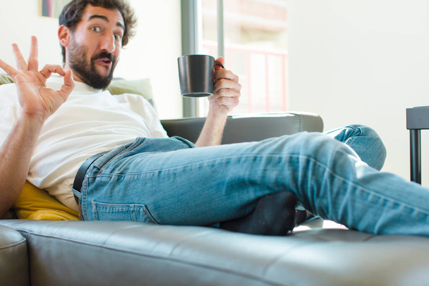 young bearded man resting on a couch with a coffee mug - Фото, зображення