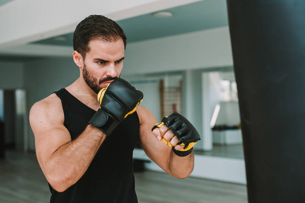 mladý muž trénuje s boxovací pytel v tělocvičně. Mužský boxer  - Fotografie, Obrázek