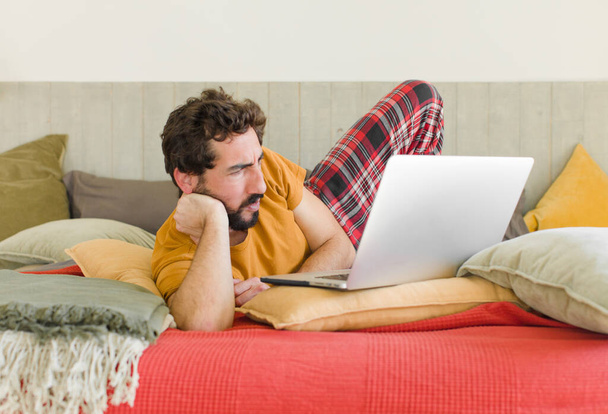 young bearded man on a bed with a laptop - 写真・画像