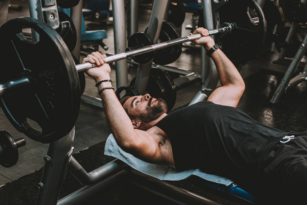 красивий м'язистий чоловік піднімає штангу в спортзалі
 - Фото, зображення