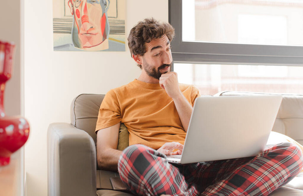 young bearded man on a couch with a laptop - Photo, Image