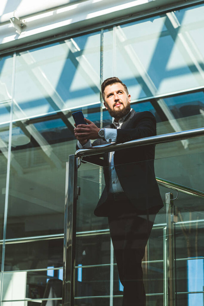 Portrait of a businessman in suit are standing on the background of glass offices. - Photo, Image
