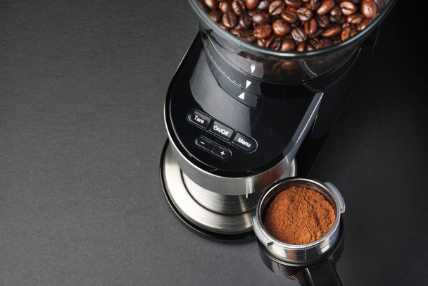 Ground coffee pouring into a portafilter holder from electric grinder - Fotó, kép