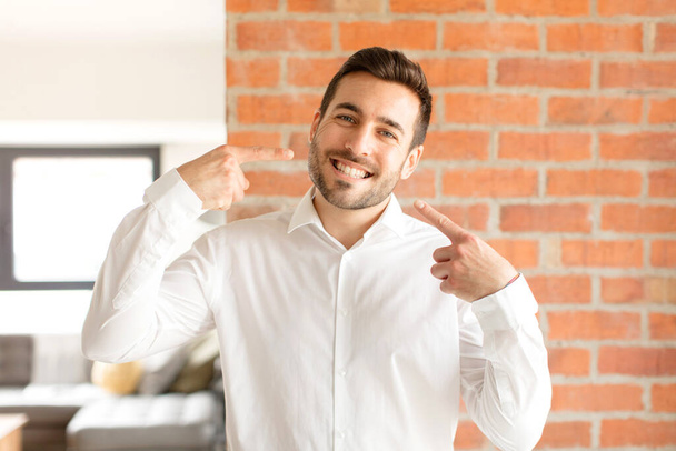 handsome businessman smiling confidently pointing to own broad smile, positive, relaxed, satisfied attitude - Photo, Image