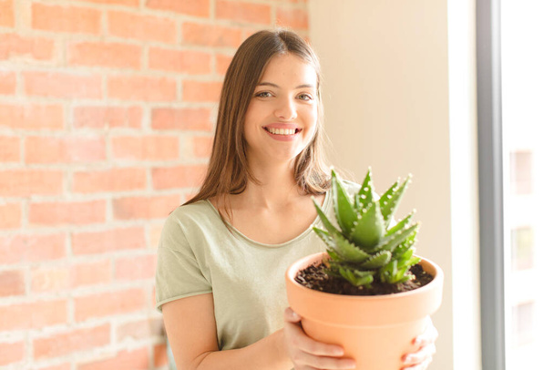 young pretty girl holding a cactus at home - Fotó, kép