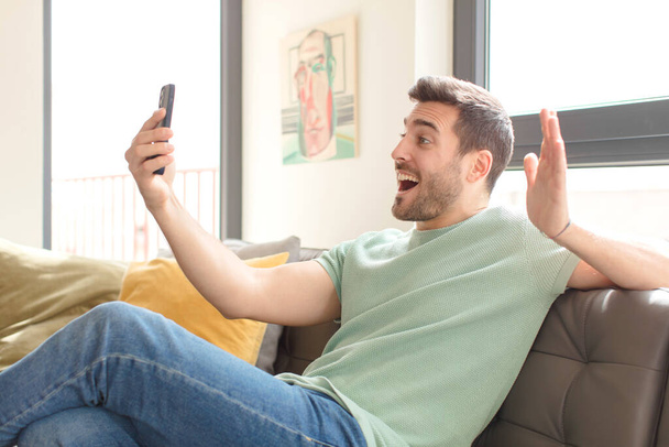 young handsome man using his smartphone at home - Foto, Bild