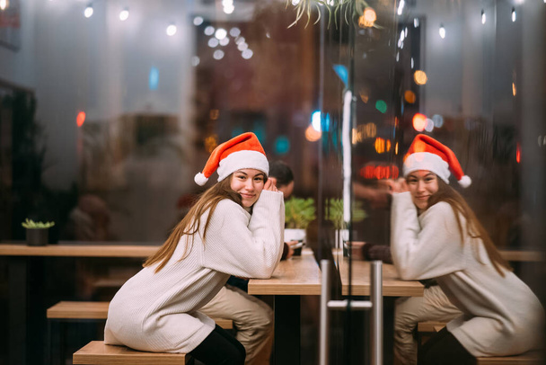 Chica con sombrero de Santa Claus sentado en la cafetería - Foto, Imagen