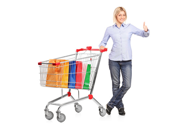 Woman with shopping cart giving thumb up  - Фото, изображение