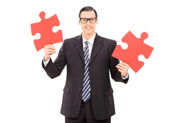 Businessman holding two pieces of puzzle - Φωτογραφία, εικόνα