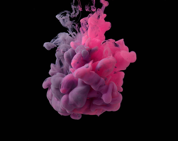 Pinke und lila Acrylfarben werden in Keulen gemischt und lösen sich in Wasser auf. Schwarzer Hintergrund. - Foto, Bild