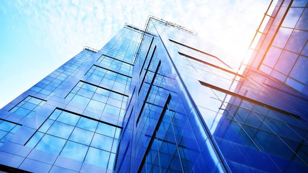 Вид снизу на современные небоскребы в деловом районе на фоне голубого неба. Смотрю на деловые здания в центре города. Восходящее солнце на горизонте.. - Фото, изображение