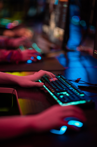 Close-up of the gamers hand movements on the glowing keyboard and mouse - Foto, immagini
