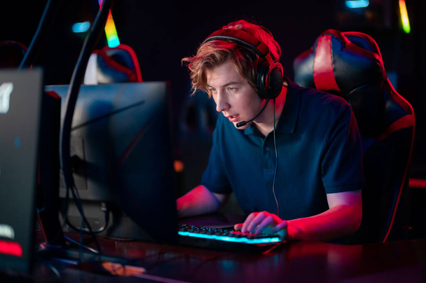Game of a young guy wearing headphones in a video game in a computer club - Photo, Image
