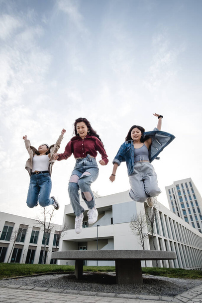 Muotokuva ryhmä aasialaisia naispuolisia ystäviä nauttimassa aikaa yhdessä hyppäämällä ilmassa ulkona. - Valokuva, kuva