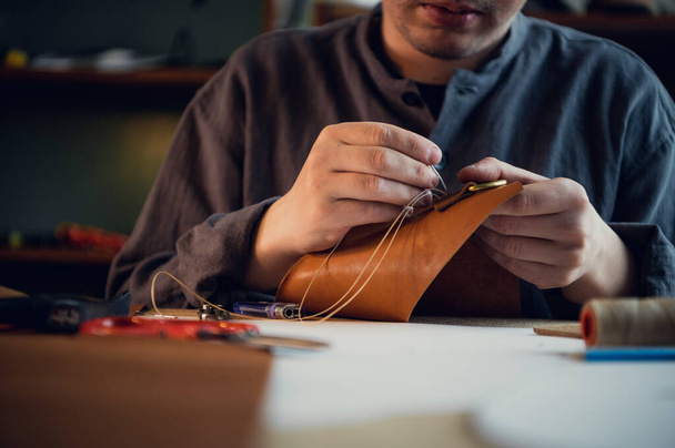 Nahaufnahme: Die Hände eines gelernten Schuhmachers machen aus echtem Leder eine Tasche - Foto, Bild