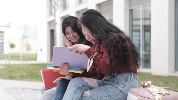 3人のアジア系の女子学生が休憩時間にキャンパスに座り - 映像、動画