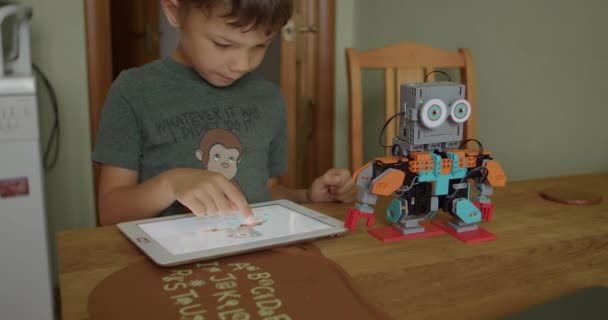 Interessierter Schüler beherrscht kleinen lustigen Roboter per Tablet - Filmmaterial, Video