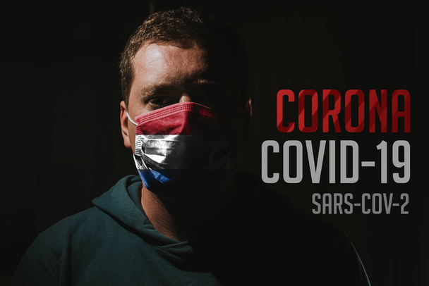 hombre con máscara con bandera de los Países Bajos para la protección contra el virus de la corona covid-19 SARS-CoV-2 - Foto, Imagen