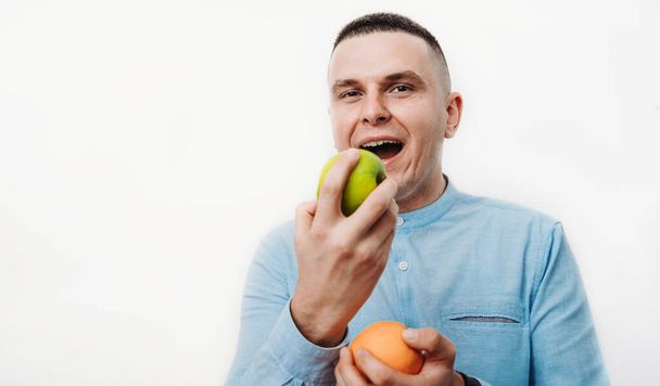 fiatal férfi, alma és narancs, fehér háttér - Fotó, kép