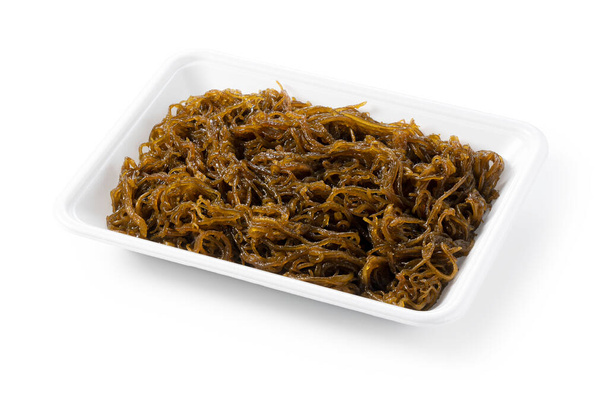 Mozuku in a food tray on a white background.Mozuku is an Okinawan delicacy. It is a kind of dark, thread-like seaweed seasoned with vinegar - Photo, Image