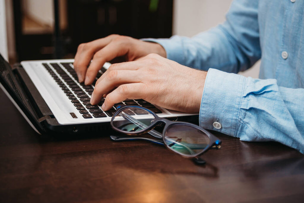 Ділова людина друкує руки на ноутбуці з окулярами на столі в офісі
 - Фото, зображення