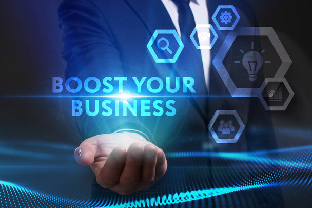 Business, Technology, Internet and network concept. Young businessman working on a virtual screen of the future and sees the inscription: Boost your business - Foto, Bild