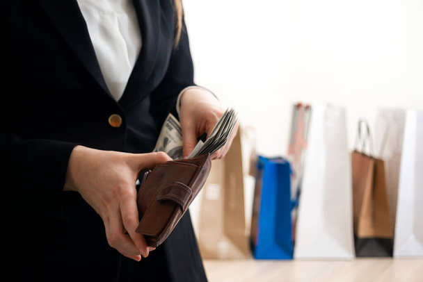 Frau zählt Dollarnoten mit Einkaufstüten im Hintergrund - Foto, Bild