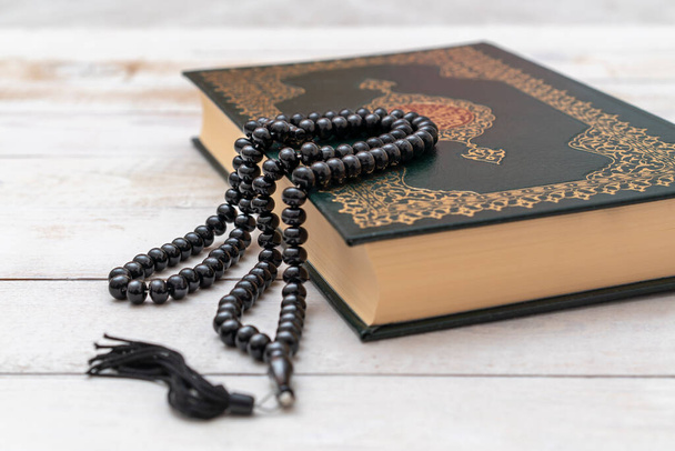 Święta Księga Islamska Koran z różańcem na drewnianym tle. Koran z napisaną kaligrafią arabską oznaczającą Al Koran. Ramadan Mubarak. Ramadan kareem.  - Zdjęcie, obraz