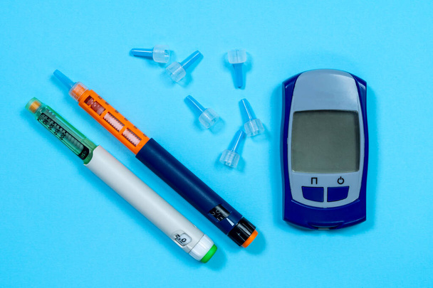インスリン注射用注射用注射ペンと針、糖尿病を持つ毎日のテスト人のための血糖値計、青の背景、トップビュー、広告のためのコピースペース。特殊第一種提供設備 - 写真・画像