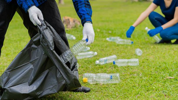 Recoger botellas de plástico en el césped en el parque limpiar el bosque ayudar a las ideas de recogida de residuos de caridad ambiental - Foto, Imagen