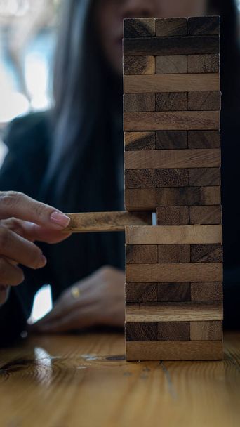 Podnikatelova ruka tahá nebo klade bloky dřeva na stůl v moderní kancelářské stavební nápady. - Fotografie, Obrázek
