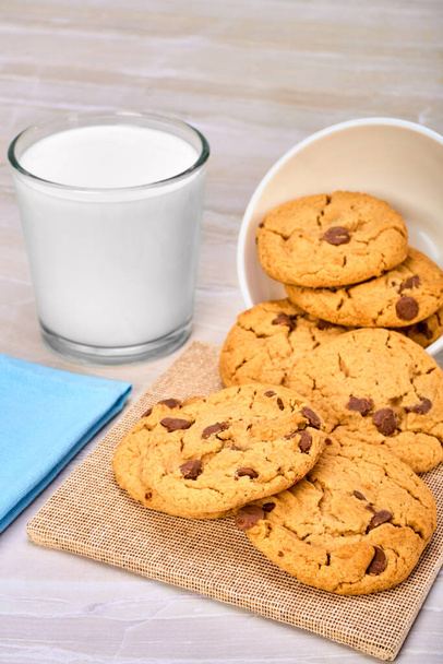 печиво з шоколадними чіпсами в білій мисці і склянка молока на мармуровій поверхні. копіювання простору для реклами
. - Фото, зображення