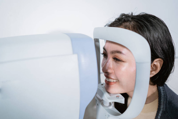 A woman is undergoing an examination using an eye examiner computer - Foto, Bild