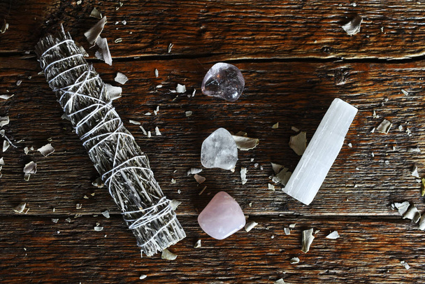 A top view image of a white sage smudge stick with healing crystals and selenite wand on a dark wooden table. - Foto, imagen