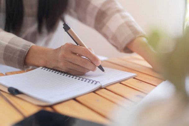 Close-up hand van het bedrijfsleven vrouwen gebruiken pen schrijven document papier. Vrouwelijke hand close-up schrijven met een blauwe pen op een wit laken. Vrouw schrijft informatie op een stuk papier. - Foto, afbeelding