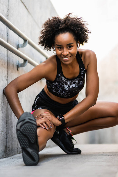 Afro athlete woman stretching legs before exercise. - 写真・画像