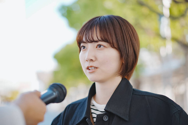 Молодая азиатка взяла интервью на улице города - Фото, изображение