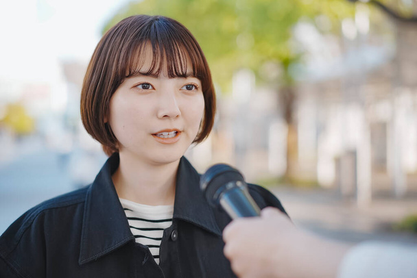 Mujer joven asiática entrevistada en la calle de la ciudad - Foto, Imagen